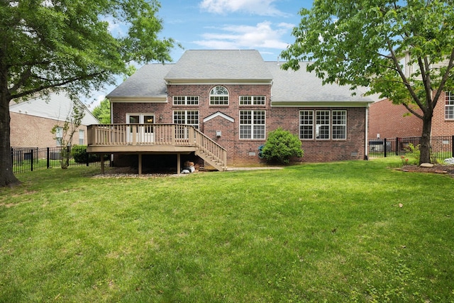 rear view of house featuring a shingled roof, brick siding, a deck, a fenced backyard, and a lawn