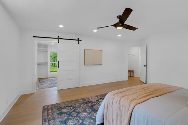 bedroom featuring recessed lighting, a barn door, light wood-style flooring, and baseboards