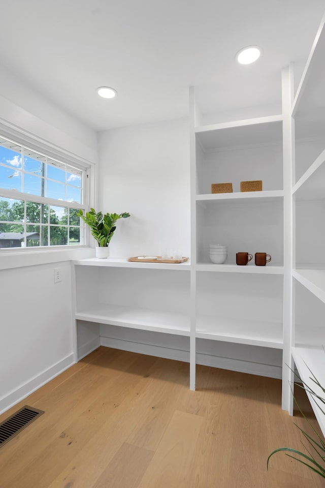 interior space featuring baseboards, recessed lighting, wood finished floors, and visible vents