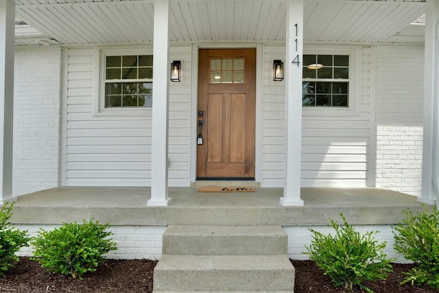 property entrance with brick siding and a porch