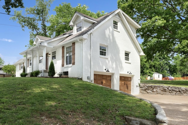 view of side of property featuring a garage, a yard, driveway, and brick siding