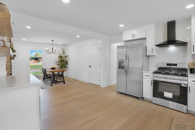 kitchen with tasteful backsplash, wall chimney exhaust hood, light countertops, stainless steel appliances, and light wood-style flooring