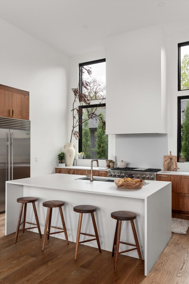 kitchen with brown cabinets, a kitchen breakfast bar, a sink, and stainless steel built in refrigerator