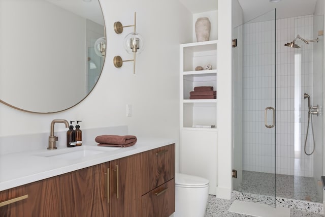 bathroom with toilet, a shower stall, speckled floor, and vanity