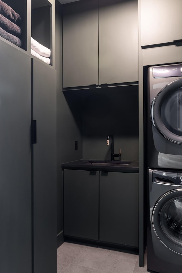 laundry room with stacked washer and dryer, a sink, cabinet space, and light tile patterned floors