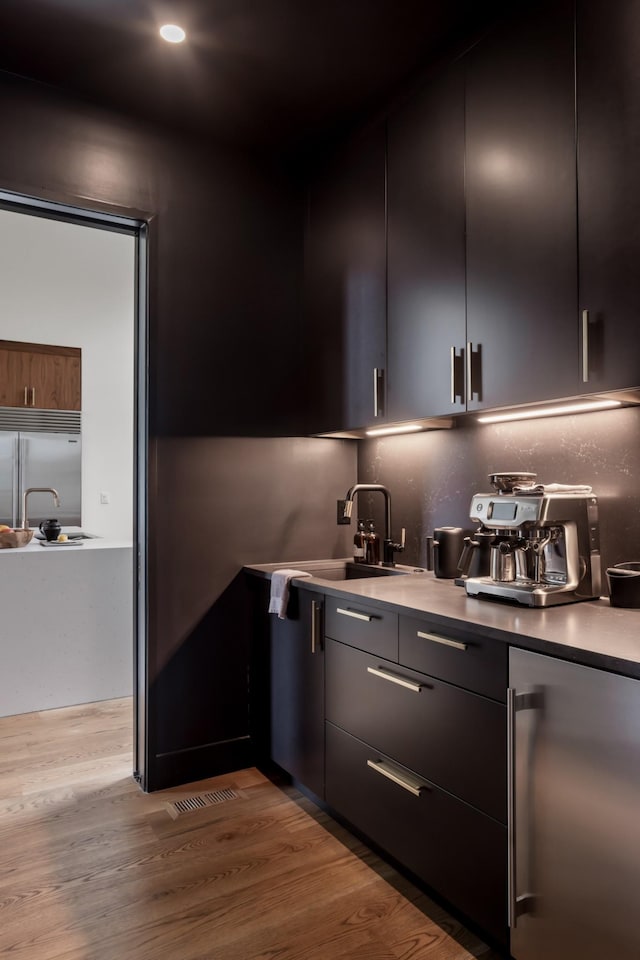 bar featuring fridge, a sink, built in refrigerator, light wood-style floors, and recessed lighting