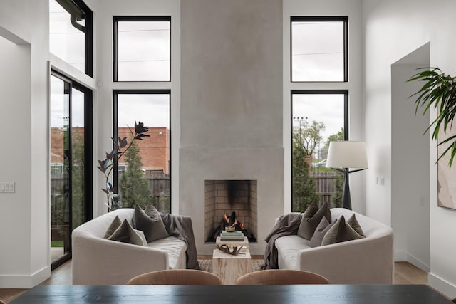 living area with light wood-style floors, a high ceiling, and a healthy amount of sunlight