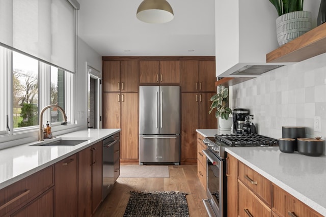 kitchen featuring backsplash, a sink, premium range hood, light countertops, and stainless steel appliances