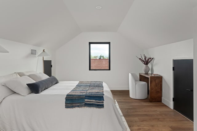 bedroom featuring baseboards, wood finished floors, and lofted ceiling
