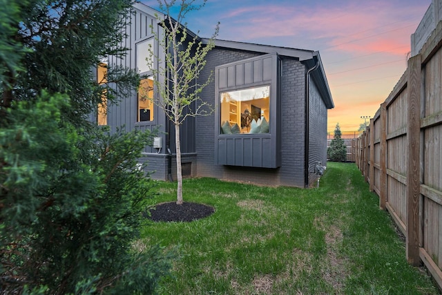 outdoor structure at dusk featuring a lawn and fence