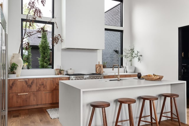 kitchen with brown cabinetry, a sink, modern cabinets, and a breakfast bar