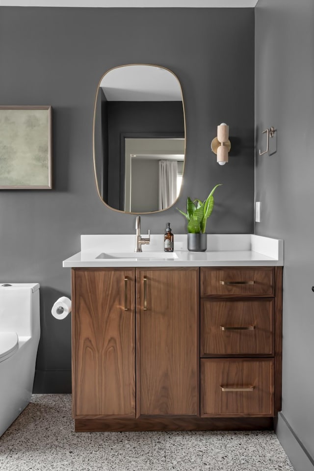 bathroom featuring toilet, baseboards, and vanity