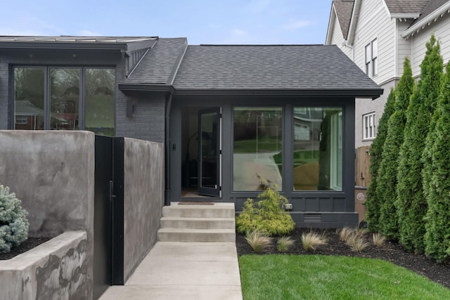 entrance to property featuring brick siding and roof with shingles