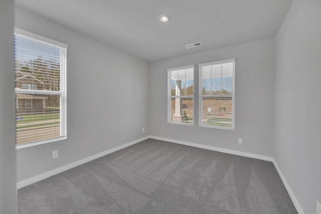 empty room featuring recessed lighting, baseboards, dark colored carpet, and visible vents