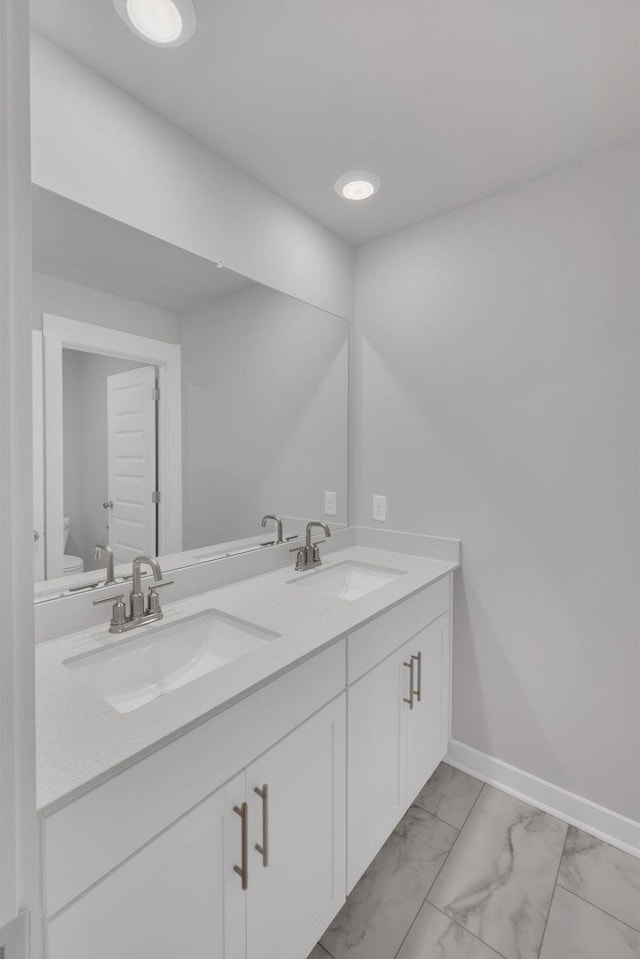 full bathroom featuring double vanity, toilet, a sink, and marble finish floor