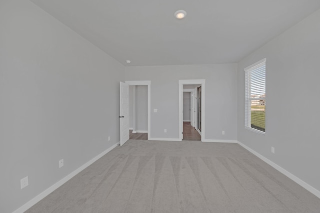 unfurnished bedroom with baseboards, a walk in closet, and carpet