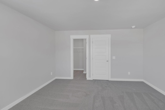 unfurnished bedroom with carpet floors, baseboards, and a spacious closet