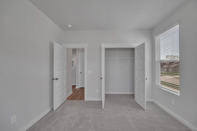 unfurnished bedroom featuring carpet floors, multiple windows, baseboards, and a closet