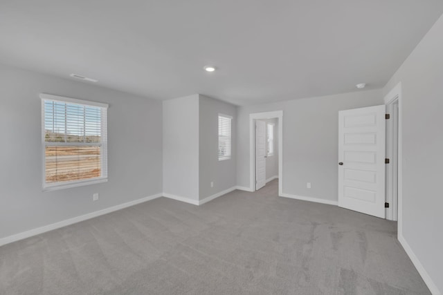 spare room featuring carpet floors, recessed lighting, baseboards, and plenty of natural light