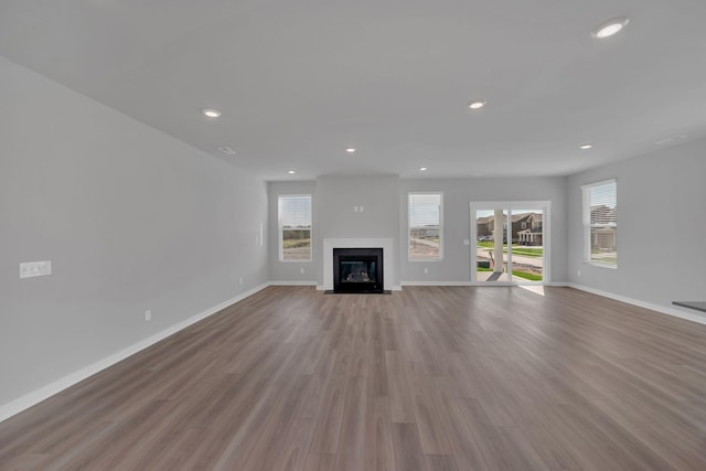 unfurnished living room with baseboards, a fireplace with flush hearth, and wood finished floors