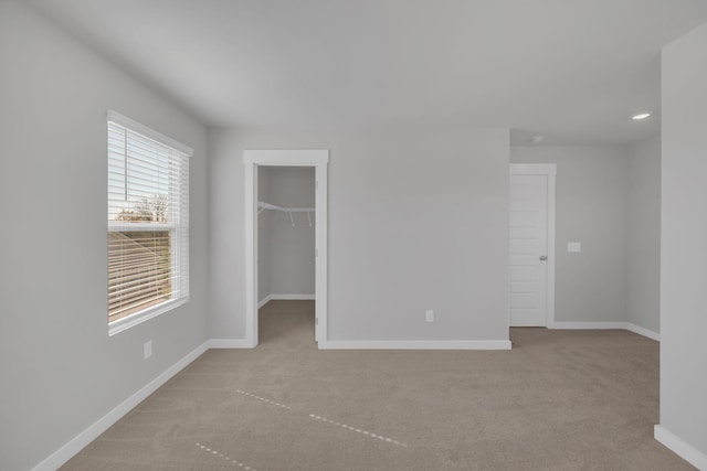 unfurnished bedroom featuring a closet, baseboards, recessed lighting, a spacious closet, and carpet flooring