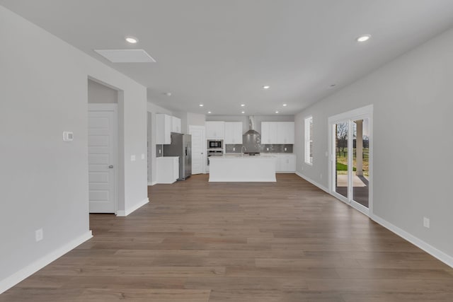 unfurnished living room with baseboards, recessed lighting, and wood finished floors