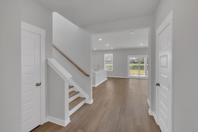 interior space featuring a sink, recessed lighting, baseboards, wood finished floors, and stairway