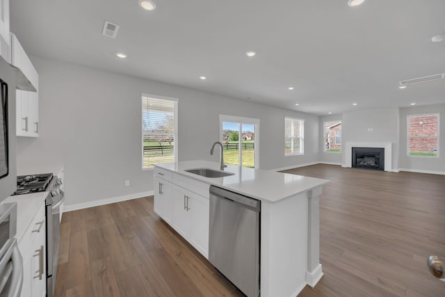 kitchen with visible vents, appliances with stainless steel finishes, wood finished floors, a sink, and light countertops
