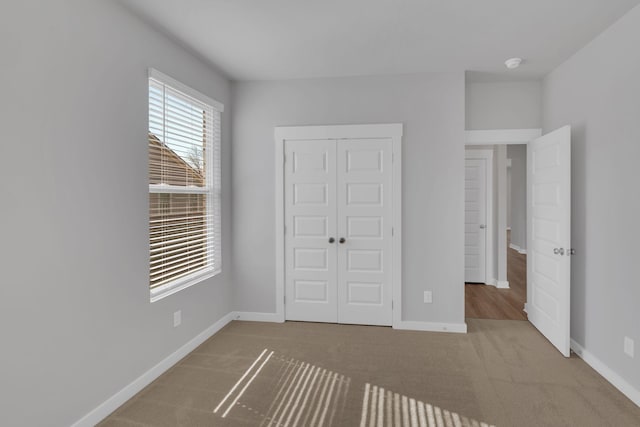 unfurnished bedroom with carpet floors, baseboards, and a closet