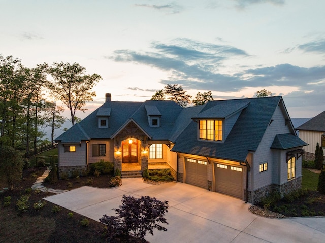 craftsman house with stone siding, roof with shingles, a chimney, an attached garage, and driveway