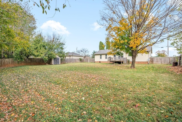 view of yard with a deck, an outbuilding, a fenced backyard, and a storage unit