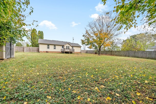 view of yard with a fenced backyard, a wooden deck, an outbuilding, and a storage shed