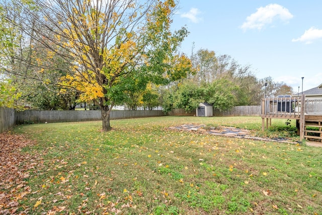 view of yard with a shed, an outbuilding, a fenced backyard, and a deck