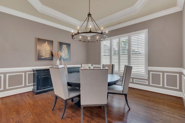 dining area featuring ornamental molding, a tray ceiling, dark wood finished floors, and a notable chandelier