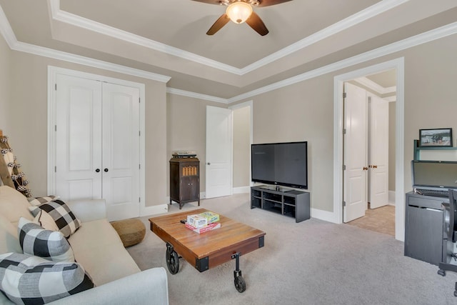 living area featuring crown molding, light colored carpet, a ceiling fan, baseboards, and a tray ceiling