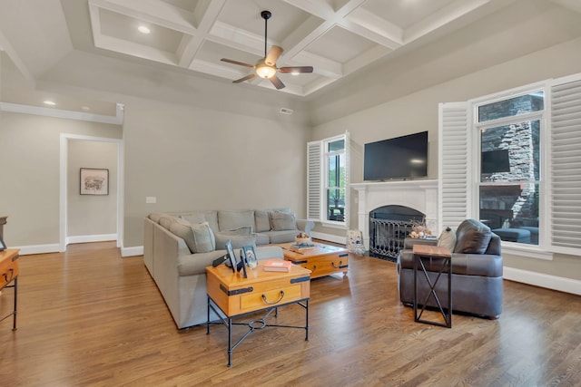 living area with a towering ceiling, a fireplace, baseboards, ceiling fan, and coffered ceiling