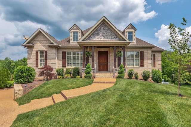 view of front of property featuring a shingled roof, a front yard, and brick siding