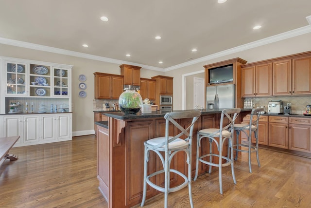 kitchen with a kitchen island, a kitchen breakfast bar, appliances with stainless steel finishes, and tasteful backsplash