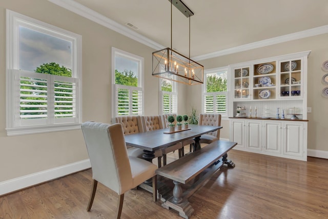 dining room featuring crown molding, a notable chandelier, baseboards, wood finished floors, and visible vents