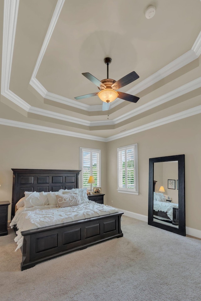 bedroom featuring carpet floors, a tray ceiling, crown molding, and baseboards