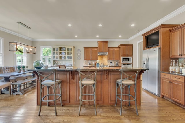 kitchen featuring brown cabinets, backsplash, appliances with stainless steel finishes, and light wood finished floors