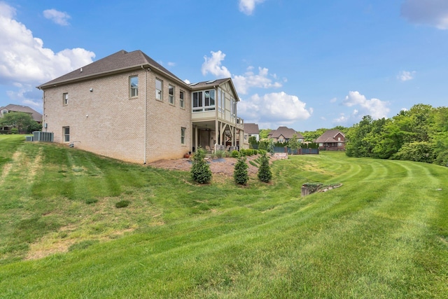exterior space with central air condition unit, brick siding, and a lawn