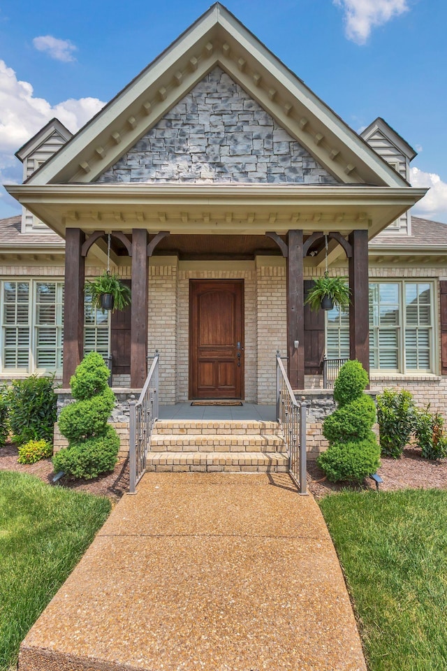 entrance to property featuring a porch and brick siding
