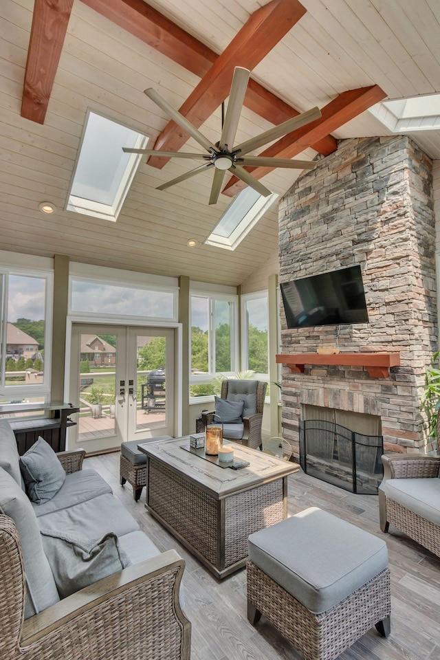 sunroom / solarium featuring a skylight, beamed ceiling, and french doors