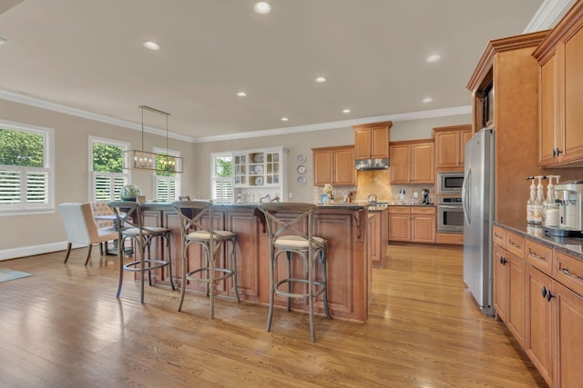kitchen featuring dark countertops, a breakfast bar area, stainless steel appliances, and light wood-style flooring