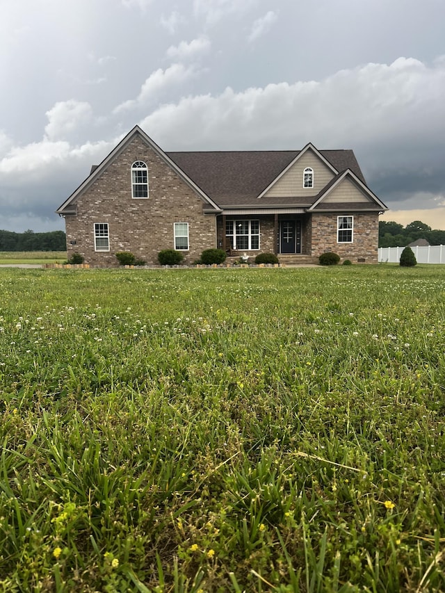 view of front of property featuring brick siding, fence, and a front lawn