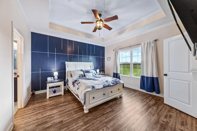 bedroom featuring baseboards, a raised ceiling, crown molding, and dark wood-type flooring