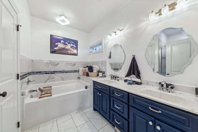 bathroom featuring marble finish floor, a bath, double vanity, and a sink