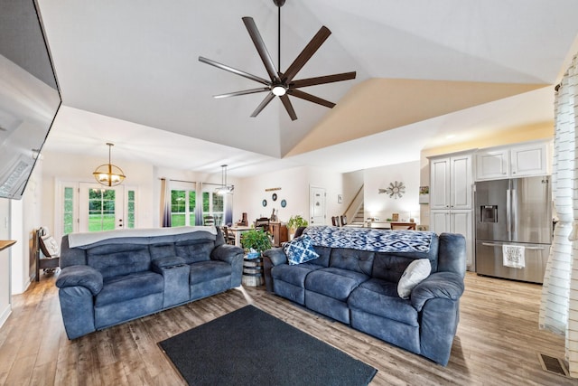 living area featuring visible vents, ceiling fan with notable chandelier, high vaulted ceiling, stairway, and light wood-type flooring