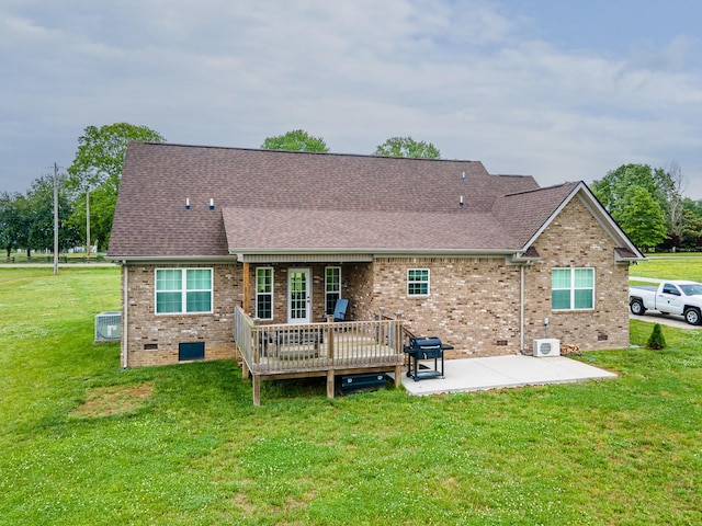 back of property with a yard, brick siding, a patio area, a shingled roof, and a wooden deck